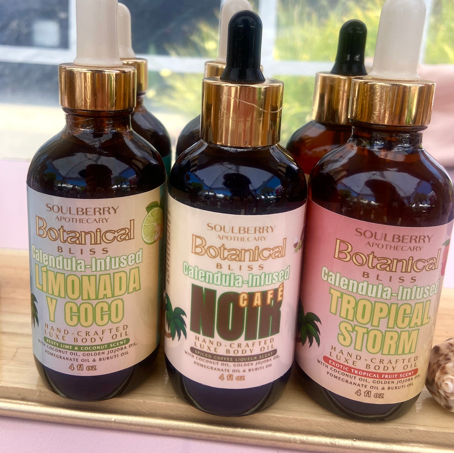 Four bottles of Soulberry Botanical Bliss body oil with droppers on a tray.