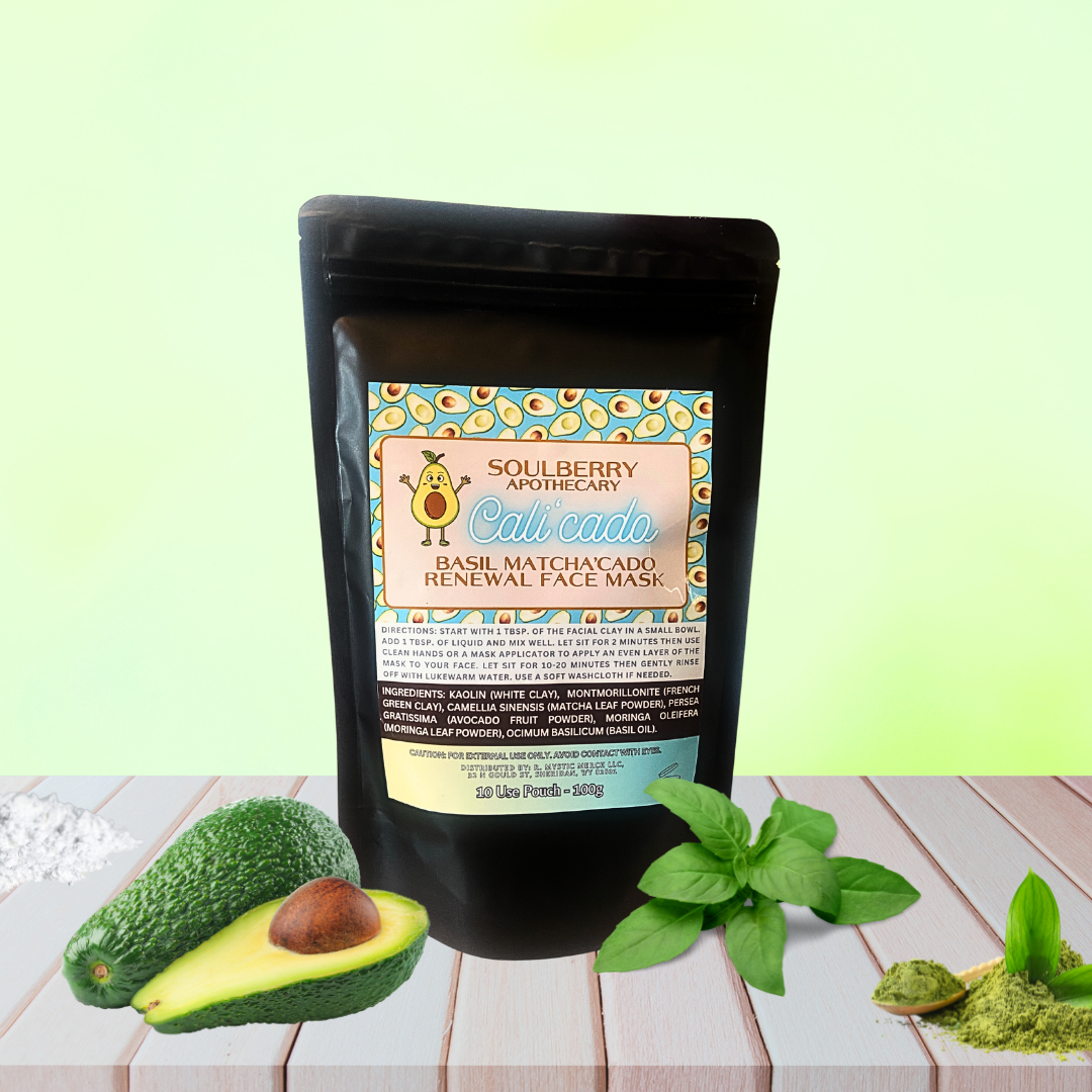 A botanical face mask product called Cali'Cado | Basil Matcha'cado RENEWAL, with a black packaging, matcha powder, avocado, and basil essential oil, displayed on a wooden surface with a green background.